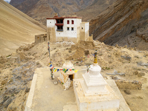 Aerial view of the historic Zanskar monastery featuring traditional white architecture and prayer flags set against the rugged mountain landscape of Zanskar, Ladakh, India.