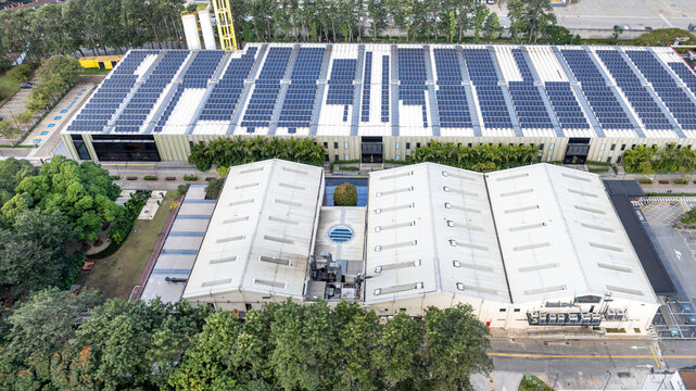 Aerial view of the Mercado Livre headquarters featuring a large rooftop solar power plant, surrounded by trees and urban infrastructure in Osasco, State of Sao Paulo, Brazil.