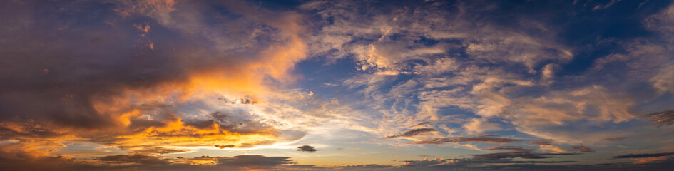 Obraz premium Sunset sky with bright colorful orange and yellow clouds. Panoramic skyscape