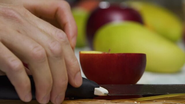 Slow motion close up of knife slicing up delicious, juicy peach