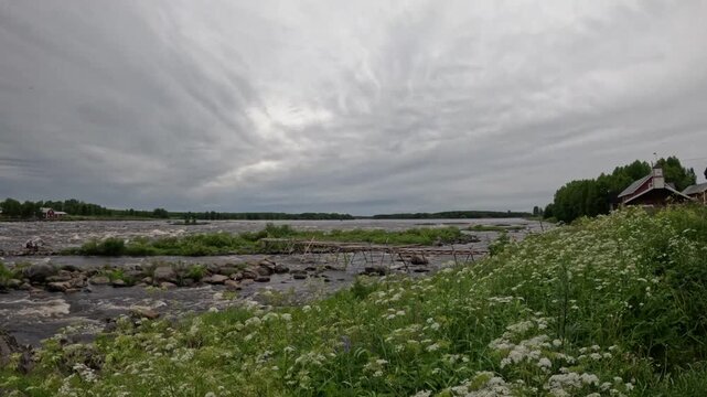 Scenic view of Kukkolankoski rapids with person in the river and wooden fishing piers