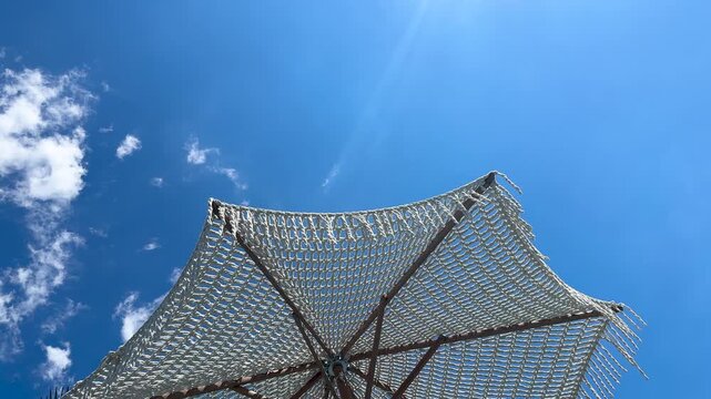 Handcrafted Macrame Beach Parasol with Fringes - Tropical Resort Scene under Sunny Clear Sky, Vacation Concept