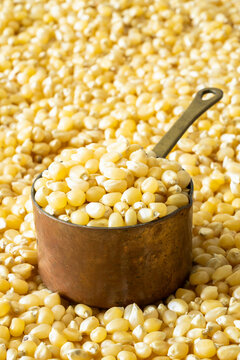Closeup of un-popped kernels of popcorn with a copper measuring cup