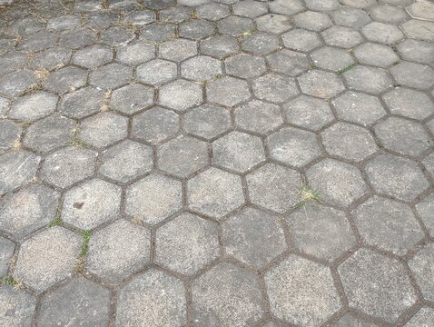 A high angle view of a weathered hexagonal concrete paver sidewalk.