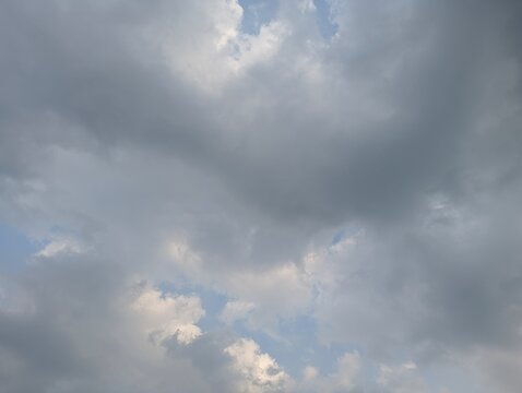 Dramatic grey storm clouds gathering in the bright blue afternoon sky.