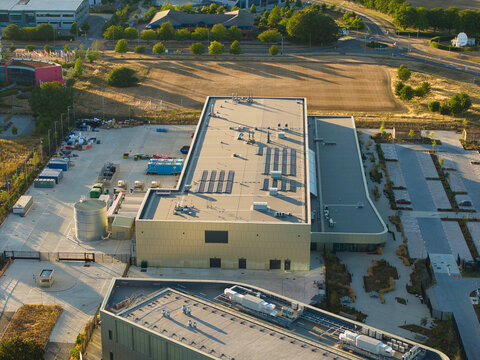 Aerial view of the Moderna Innovation and Technology Centre featuring a modern building with solar panels, adjacent parking, and surrounding landscape in Harwell Oxford, England, United Kingdom.