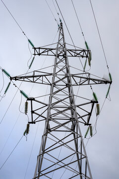 Steel transmission line support structure and high-voltage power line support structure. Network infrastructure with glass insulators distributes electricity, viewed from below.
