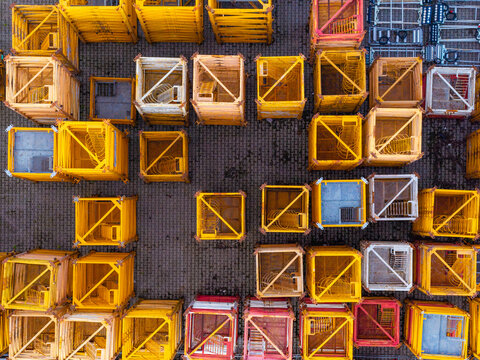 Aerial view of tower crane mast sections arranged in a grid pattern on a paved surface in Masovian Voivodeship, Poland.