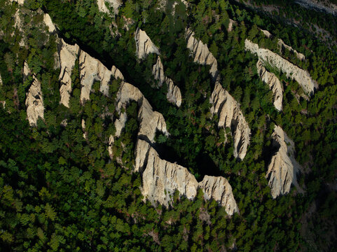 Aerial view of sharp, eroded rock formations rising through a dense green forest in Nepal.