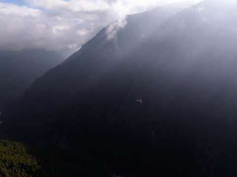 Aerial view of a helicopter flying over the rugged, misty mountains of the Himalayas in Nepal.