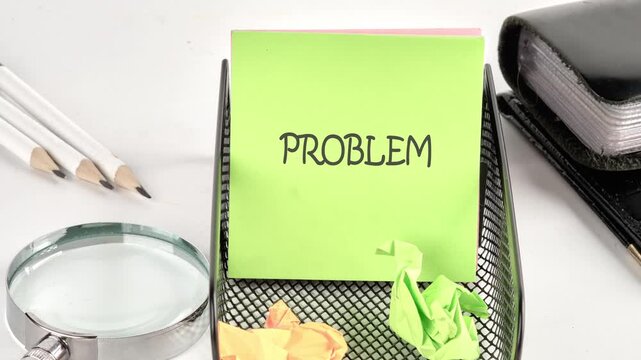 A person works on a paper with letters. They use an eraser and colored pens to form words. This happens on a desk with supplies