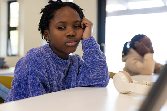Diverse teen females sitting in classroom African American in blue top resting head cream headset