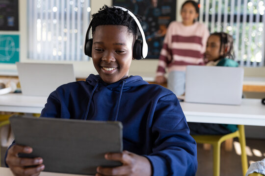 Female students sitting in classroom youth African-American student using tablet wearing headphones