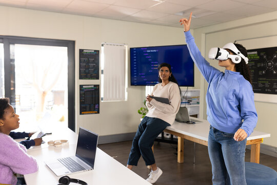 Diverse female students using virtual reality in lab with VR headset, laptops, display, copy space