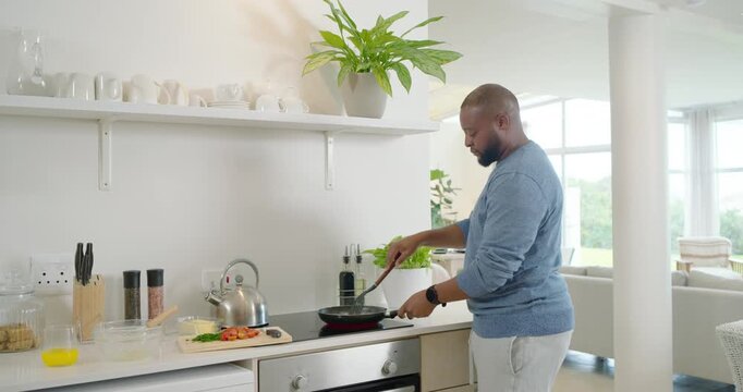 African American man making meal lifting frying pan, stirring and seasoning at hob, copy space