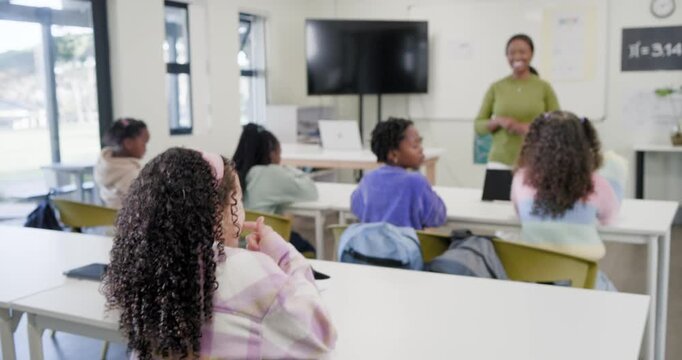 African American teacher with six girls responding to hand raise, explaining pi on classroom board