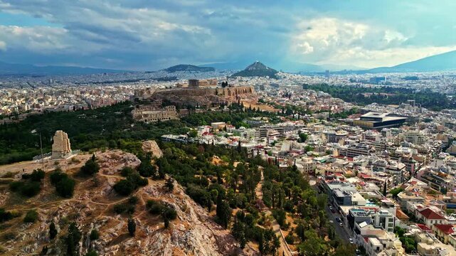 Aerial view of the Acropolis of Athens with the Parthenon and surrounding historic city landscape under a cloudy sky in Athens, Attica, Greece.