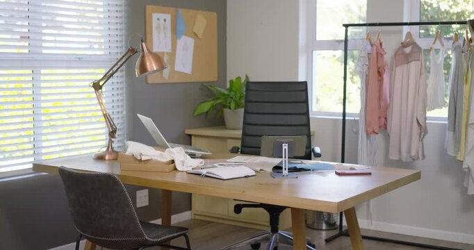 Cam is sliding forward and right, revealing wooden desk near window with laptop for design review