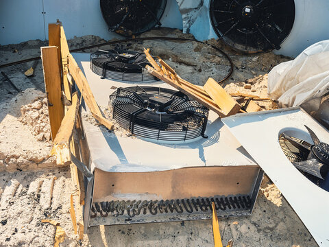 Damaged HVAC unit with exposed components and fan blades on a rooftop