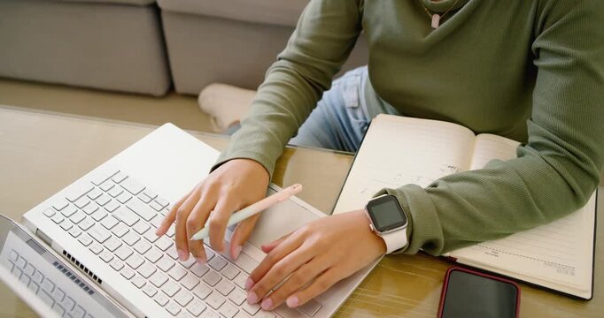 African American woman working on sofa shifting from notebook to laptop typing notes, copy space