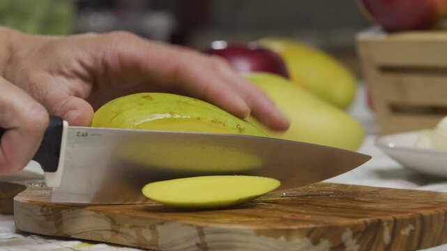 Chef using large knife to slice up mango in slow motion