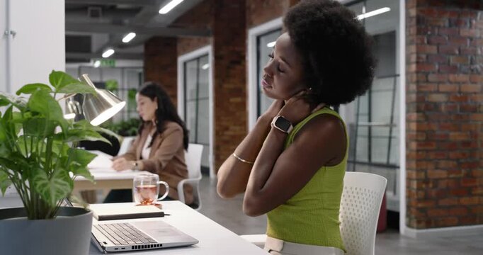 Coworkers at desk woman lime top stretching rubbing neck relieving ache typing laptop, copy space