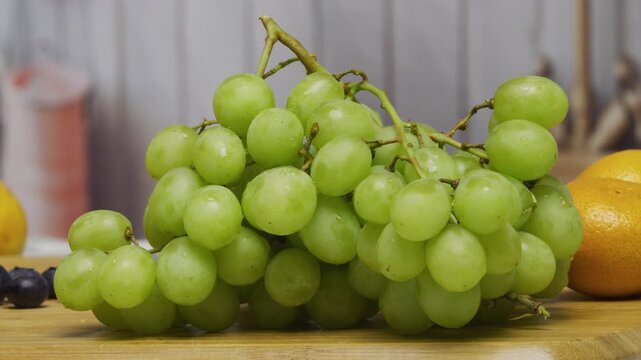 Vine of green grapes sitting on chopping board in Kitchen - closeup shot