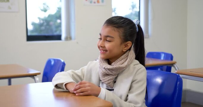 African American preteen girl turning head smiling while gaze shifting at school desk with scarf