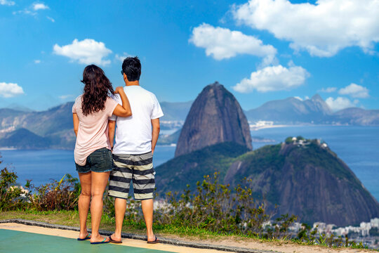 Rear view of a couple enjoying the panoramic view of Sugarloaf Mountain and Guanabara Bay from Mirante Dona Marta in Rio de Janeiro, Brazil.