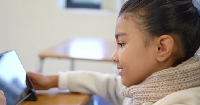 African American school-age child girl sitting in class using tablet stand, wearing scarf learning