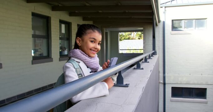 African American girl leaning on balcony railing with phone and scarf, tapping, checking messages