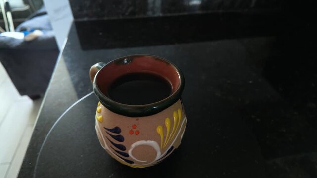 Traditional mexican coffee mug with dark brew rotating on a countertop