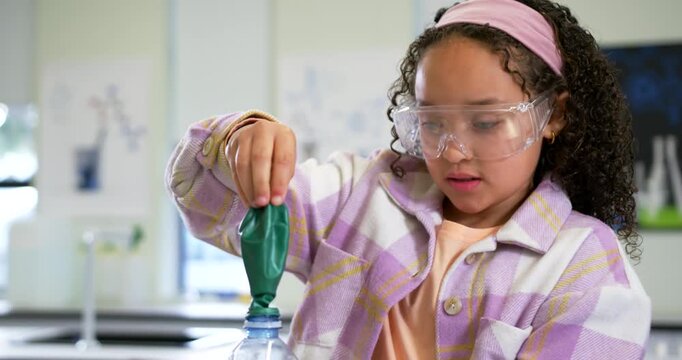 African American child fitting balloon onto bottle in school lab, goggles on, showing foam reaction