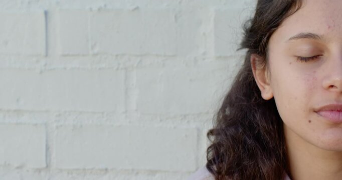 African American teen resting eyes closed opening eyes smiling against white brick wall, copy space