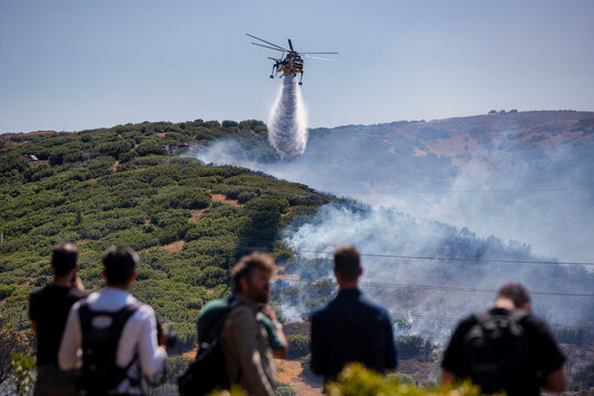 Firefighting Helicopter Battling Derveni Wildfire as Onlookers Observe the Operation