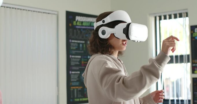 Teenage female student raising hands and putting on white VR headset in lab interacting virtually