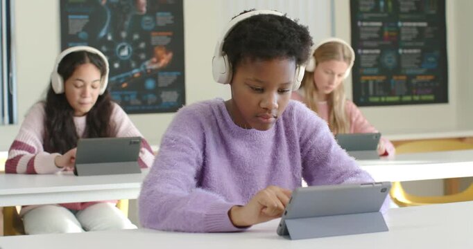 African teen girls white-phones tapping tabs in class camera moving, center girl purple top smiling