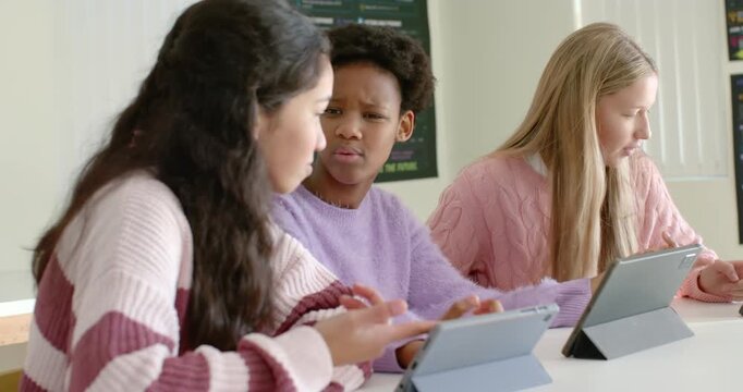 Diverse teen females helping after center student vocalizing confusion, tapping tablets at school