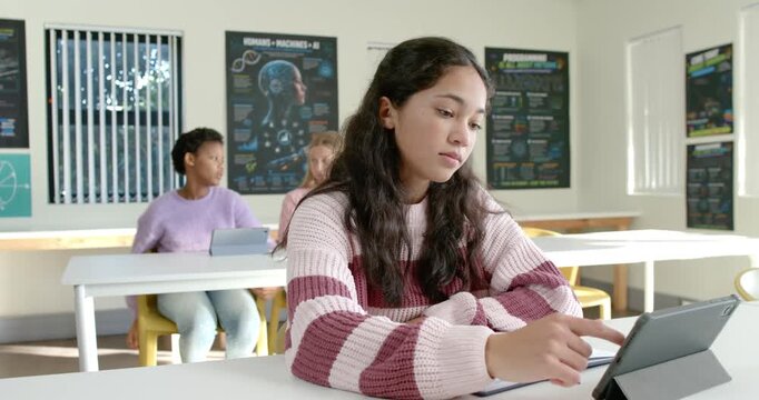 Teen peers watching front female tapping tablet, noting, pausing and seeing motion right in class