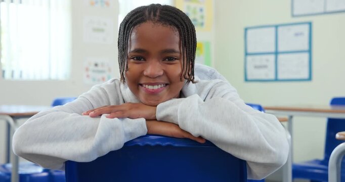 Teenage male student turning leaning on chair back, smiling as camera moving closer in classroom