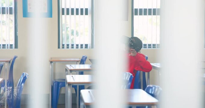Teen male in red sweater placing VR headset at school, adjusting and exploring lesson with tablet