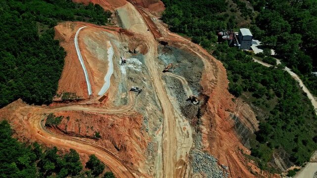An aerial perspective of a large-scale railway construction project in Greece, featuring heavy machinery and earthworks, captured on May 26, 2024.