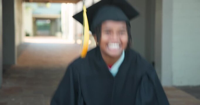 African American male youth reacting to graduation, raising cap tassel in campus hall wearing gown