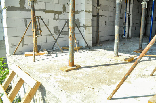 Construction site with concrete blocks and scaffolding poles supporting a new structure