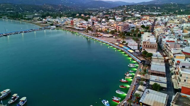 Aerial view of Crete harbor with moored boats along the quay and waterfront buildings in Greece.