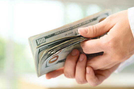 Person counting a stack of united states hundred dollar bills, financial transaction and wealth management