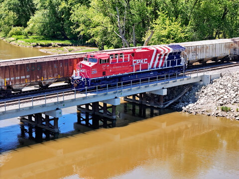 Savanna, Illinois May 14, 2026 CPKC 776 America 250 commemorative locomotive in patriotic red and blue livery colors crossing a bridge along side a second train.
