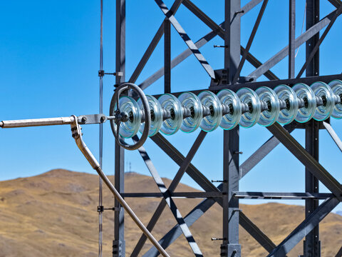 Glass insulator string on an electrical transmission tower against the blue Andean sky