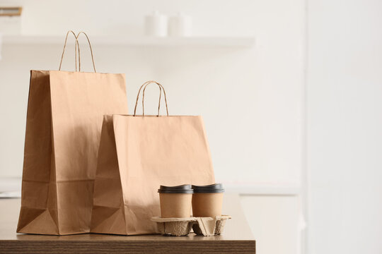 Paper bags with coffee cups on table in kitchen. Food delivery service