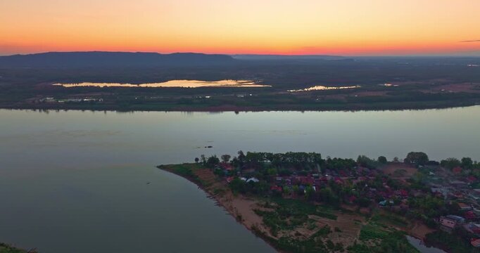 Scenic panorama capturing the tranquil flow of the Nam Kading River beneath a glowing sunset sky, highlighting natural beauty and local infrastructure.